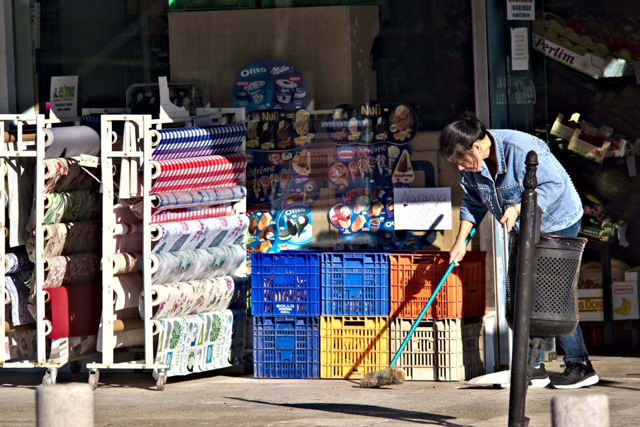A woman sweeps the sidewalk outside a busy shop in Seville, Spain.